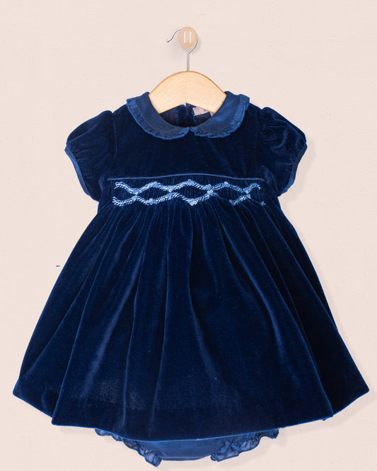 Navy blue velvet dress with lace details on a beige background