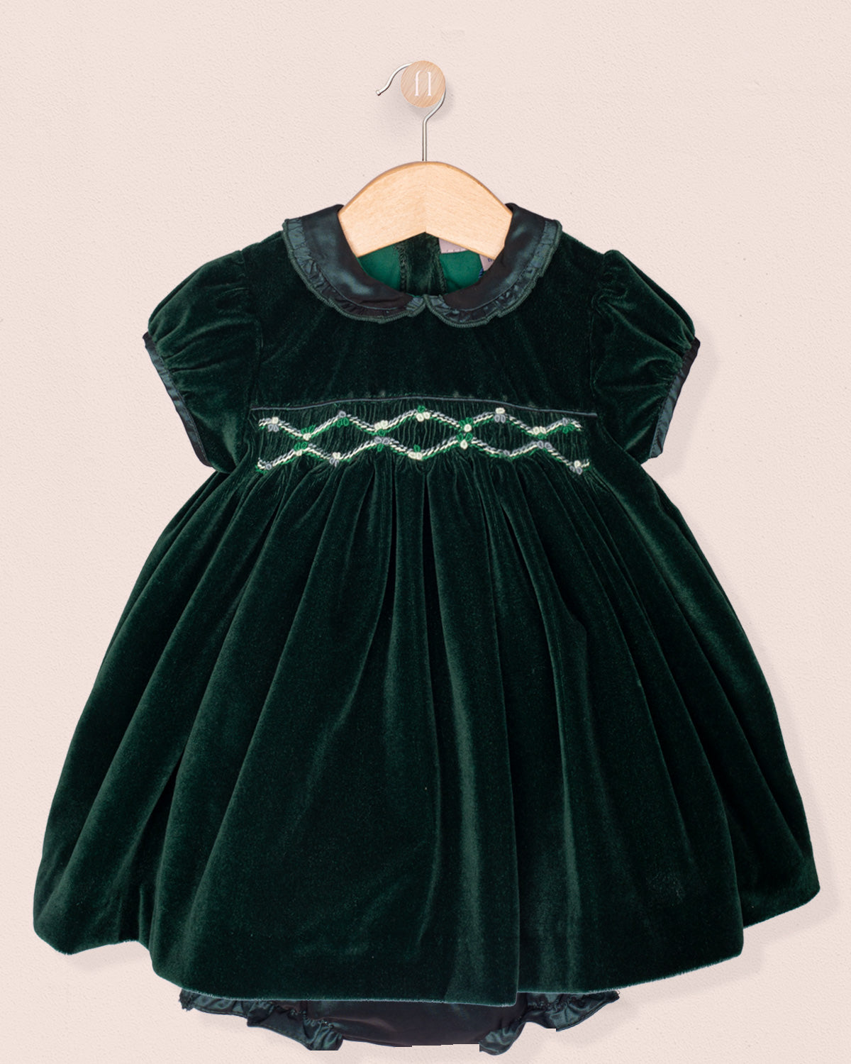 Green velvet dress with embroidered details on a beige background