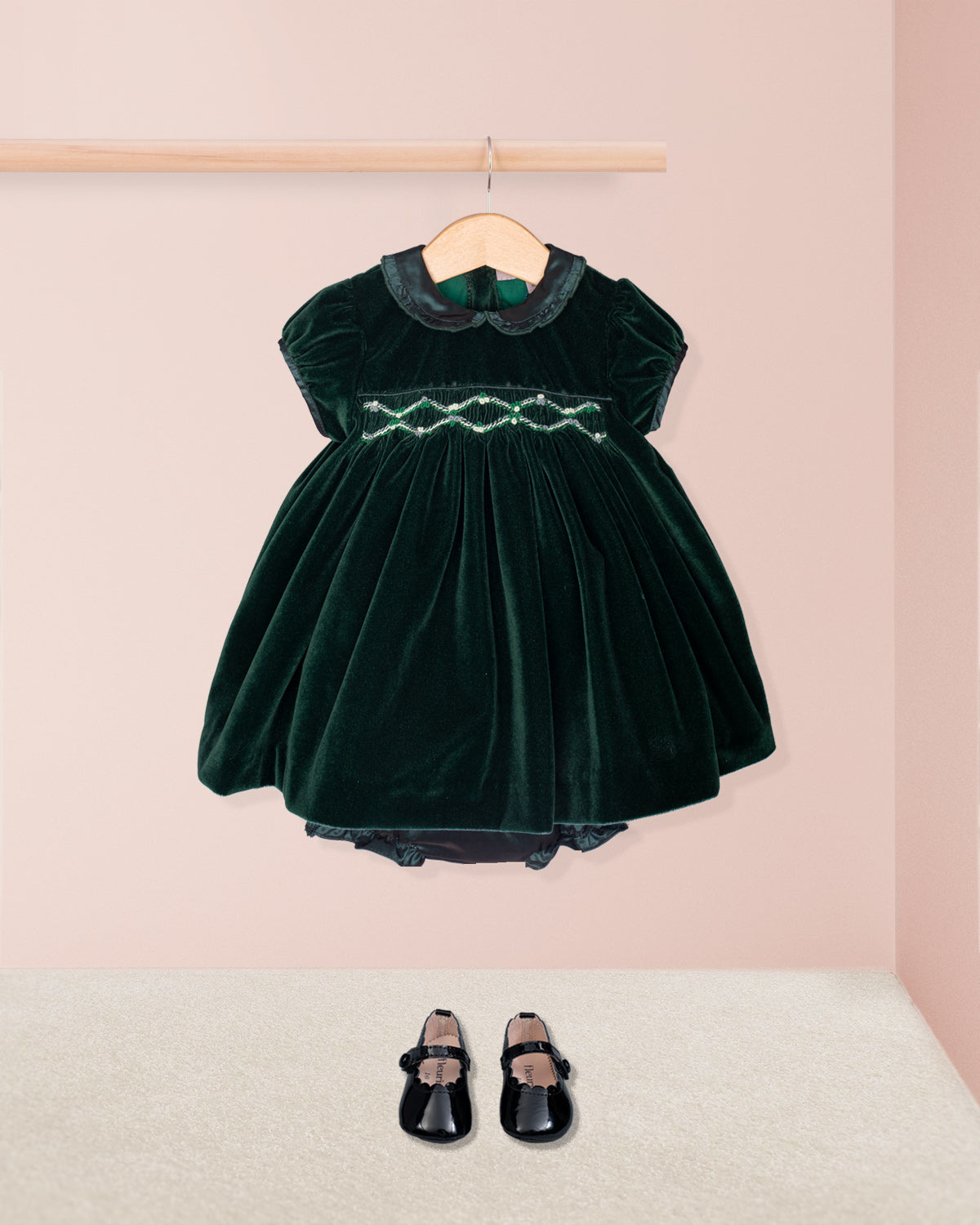 Green velvet dress with black shoes on a pink background