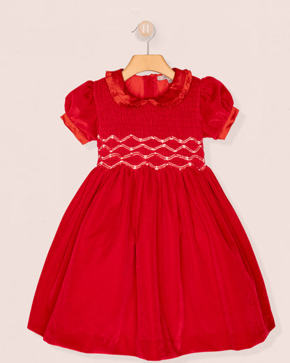 Red dress with white smocking on a beige background