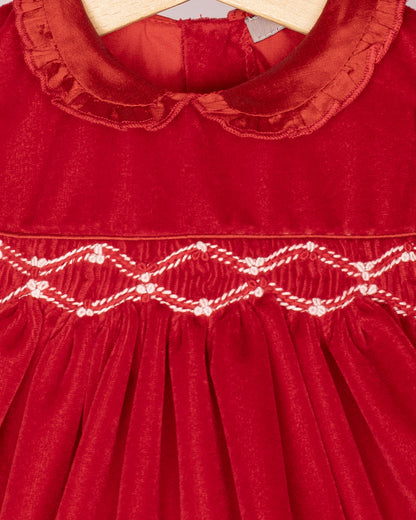 Red velvet dress with smocked details on a hanger