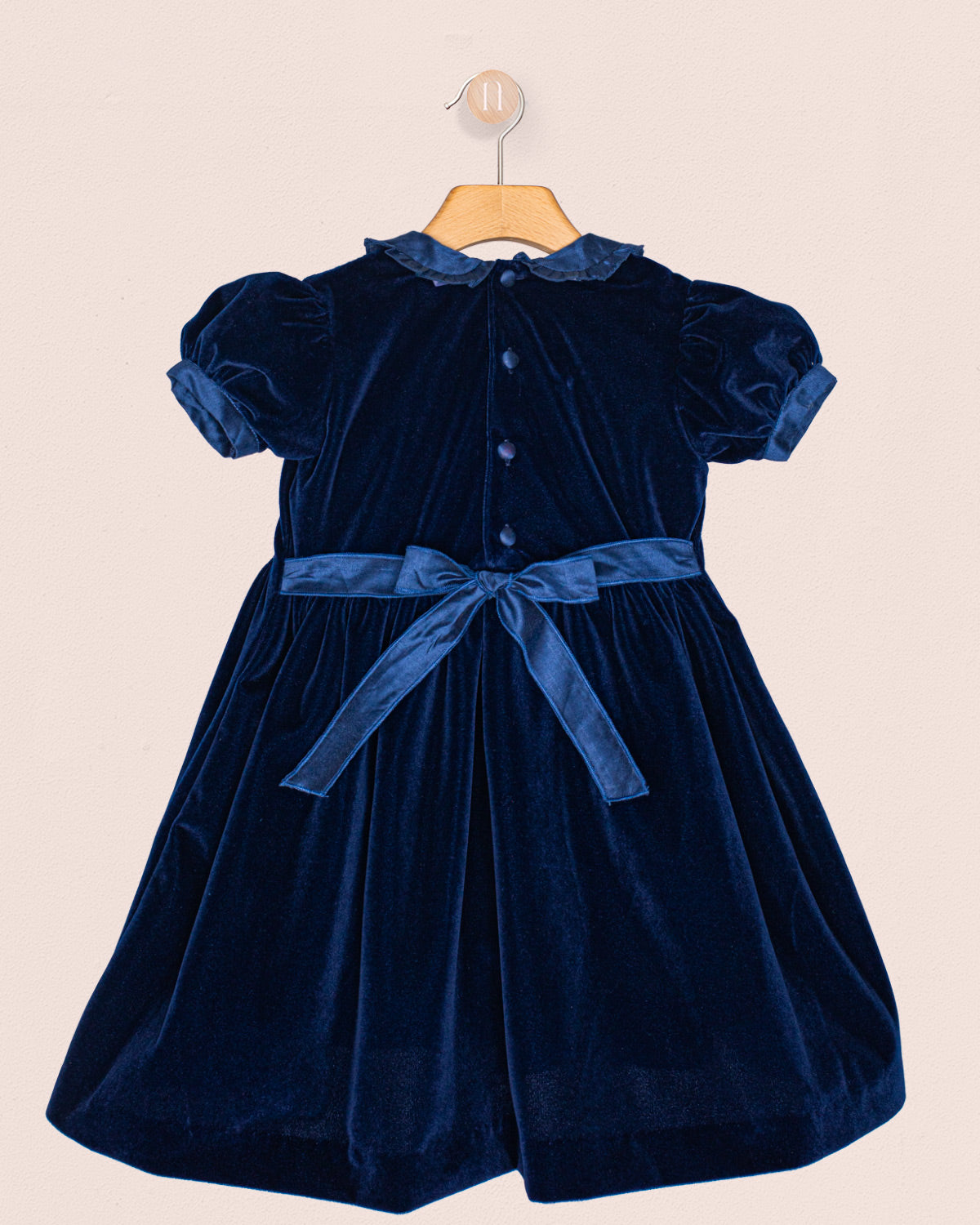 Navy blue velvet dress with a belt on a beige background back view
