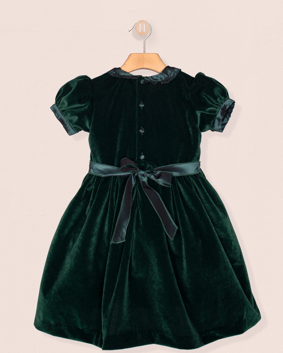 Green velvet dress with a belt on a beige background
