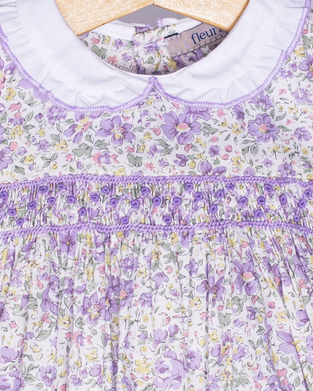 Close-up of a floral dress with purple accents on a hanger.