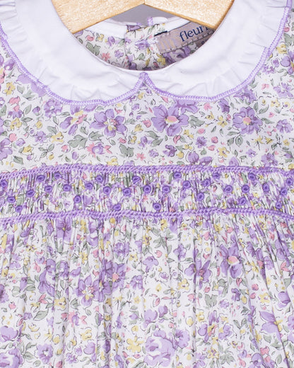 Close-up of a floral dress with purple accents on a hanger.