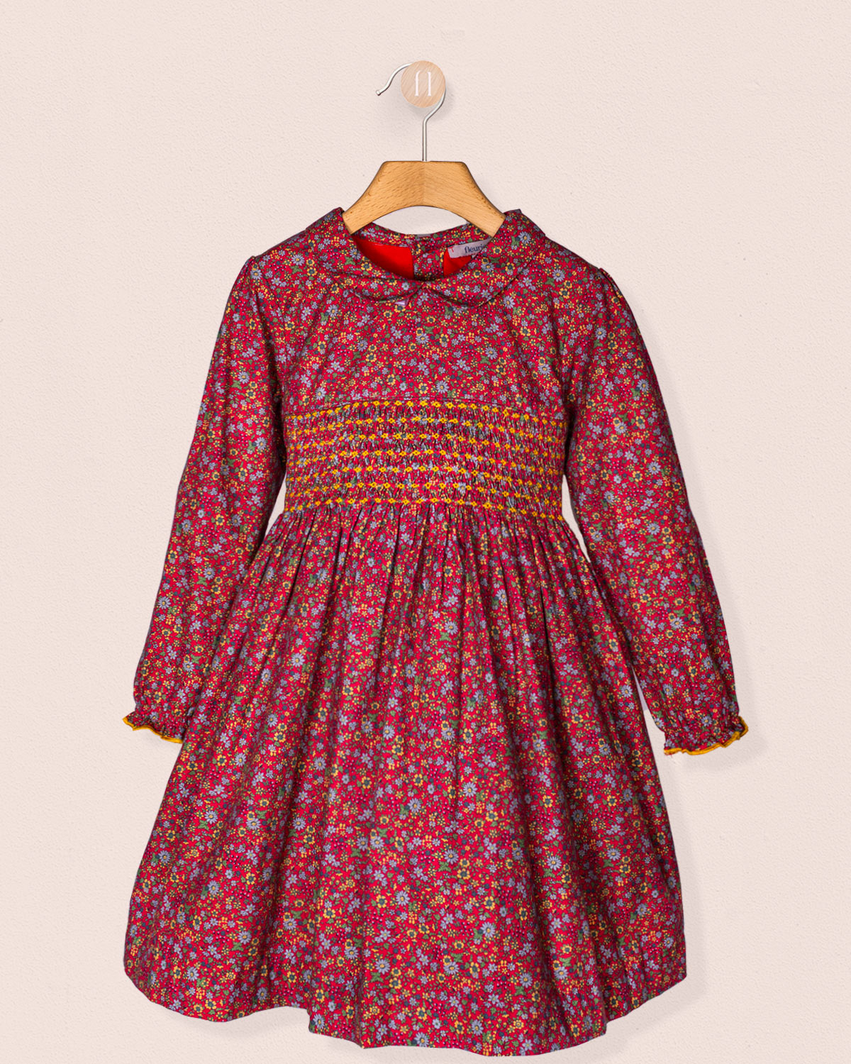 Red floral dress with smocked waist on a beige background