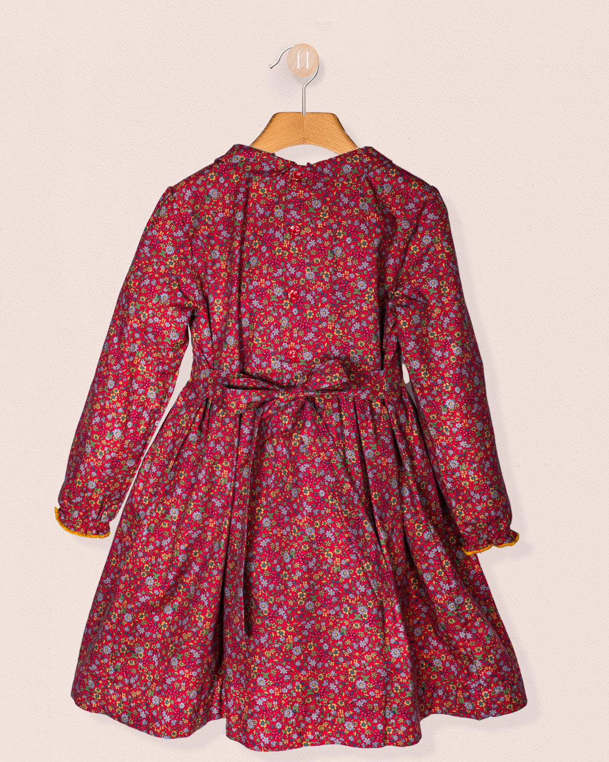 back view Red floral dress on a hanger against a beige background