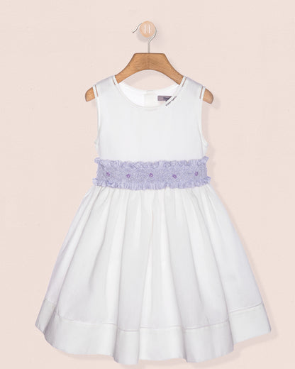 White dress with a purple embellished waistband on a beige background