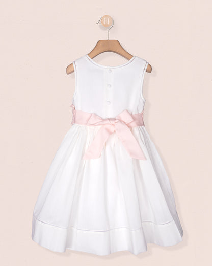 White dress with a pink bow on a beige background