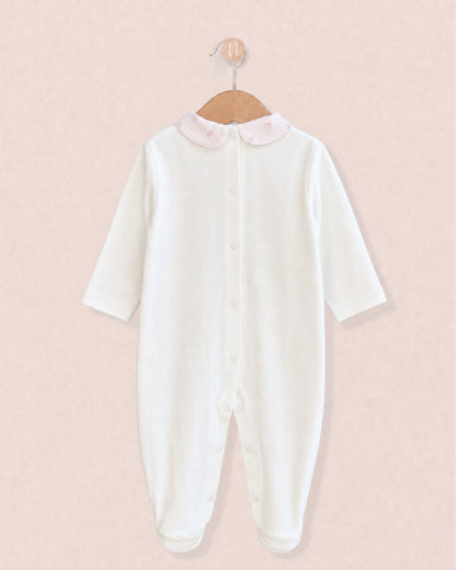 Back of white cotton baby onesie hanging from wooden hanger, with light pink floral motif collars.