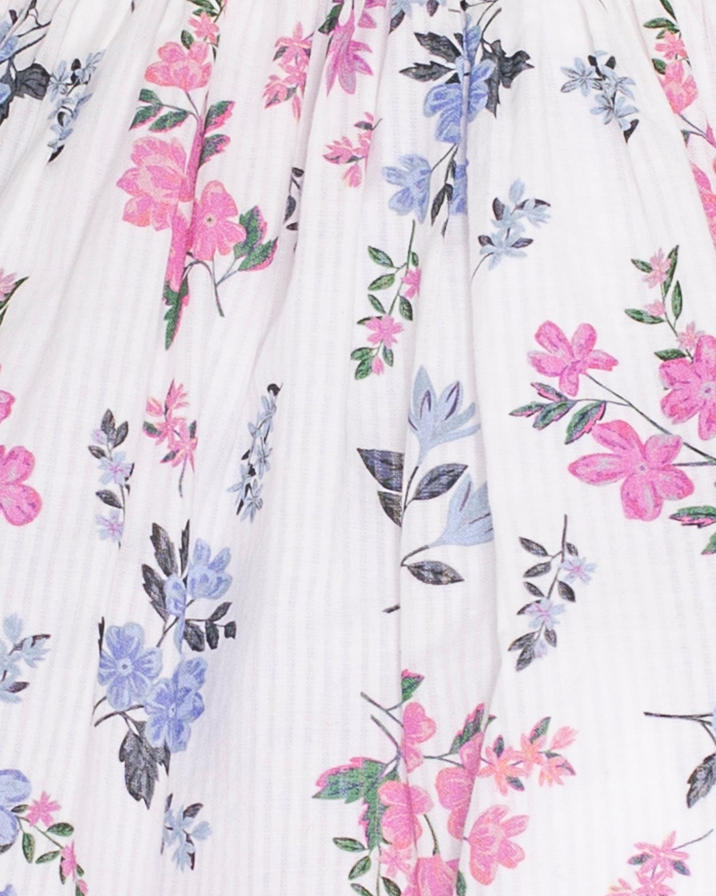 Detail of pink smocking across the bodice and delicate pink and purple floral print on white cotton voile fabric with fine vertical texture.