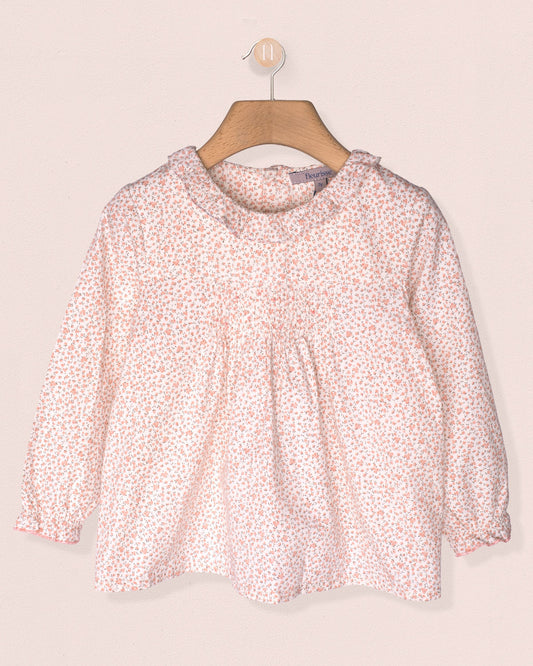 Pink floral blouse on a hanger against a light pink background