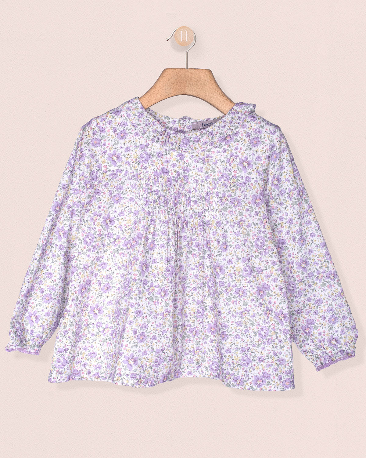Floral blouse on a hanger against a beige background