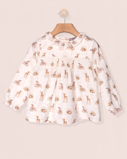 White blouse with animal print on a wooden hanger against a beige background