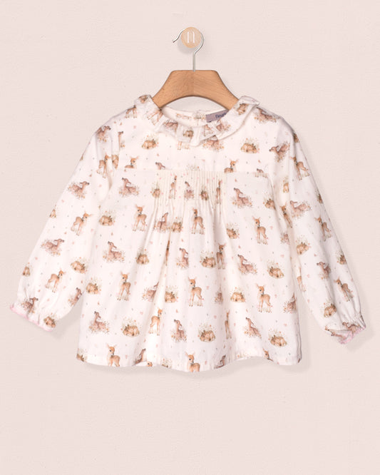 White blouse with animal print on a wooden hanger against a beige background