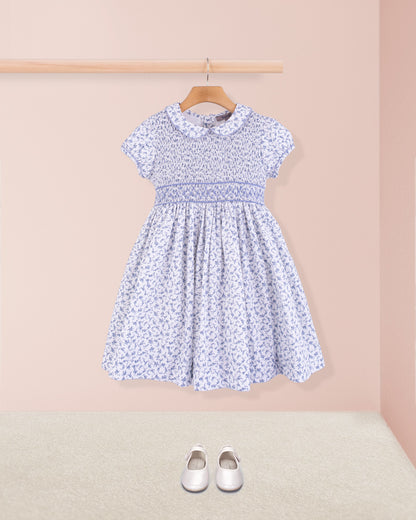 Full front view of Amanda Campari blue floral smocked dress with white Mary Jane shoes beneath