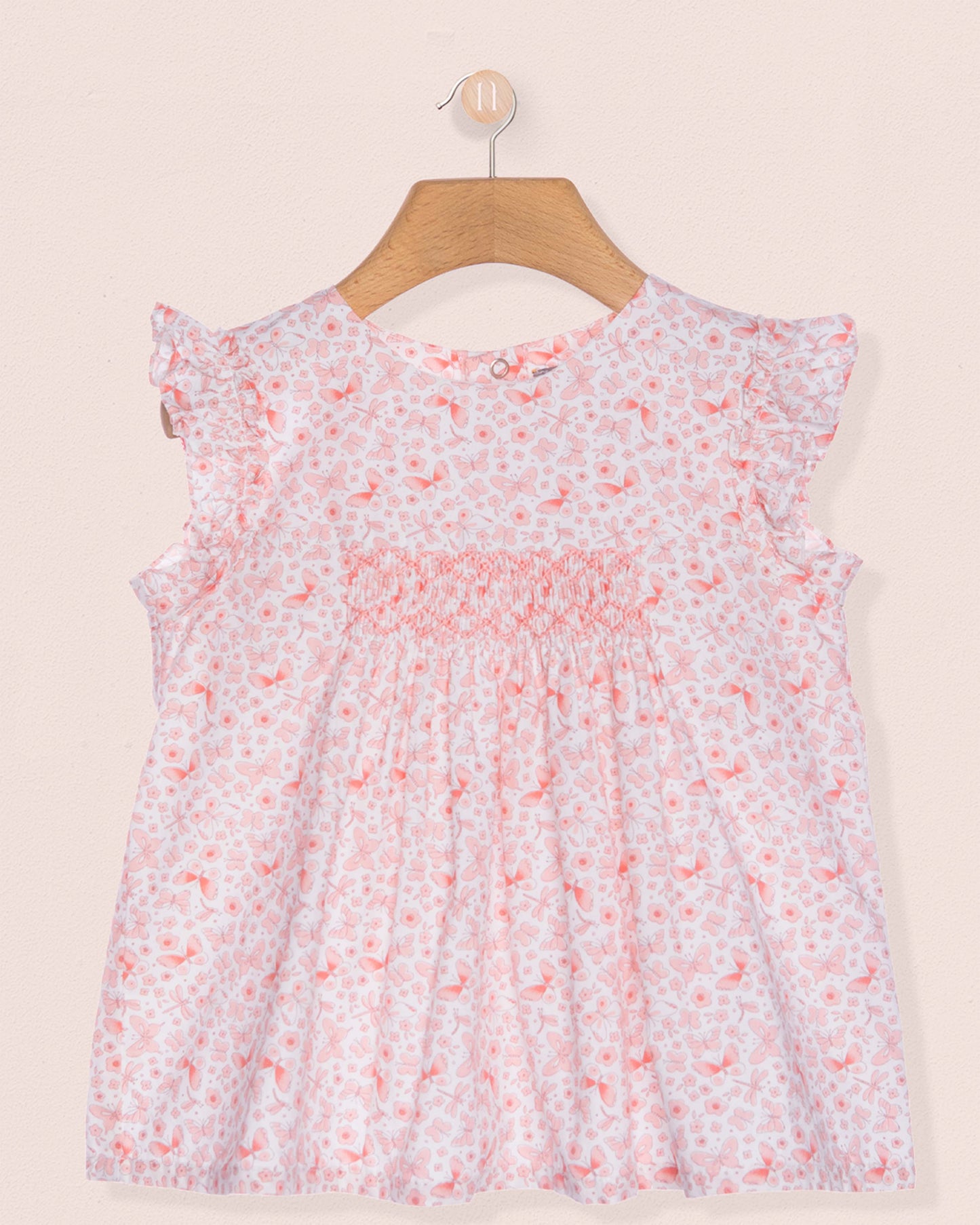 Floral dress on a hanger against a beige background