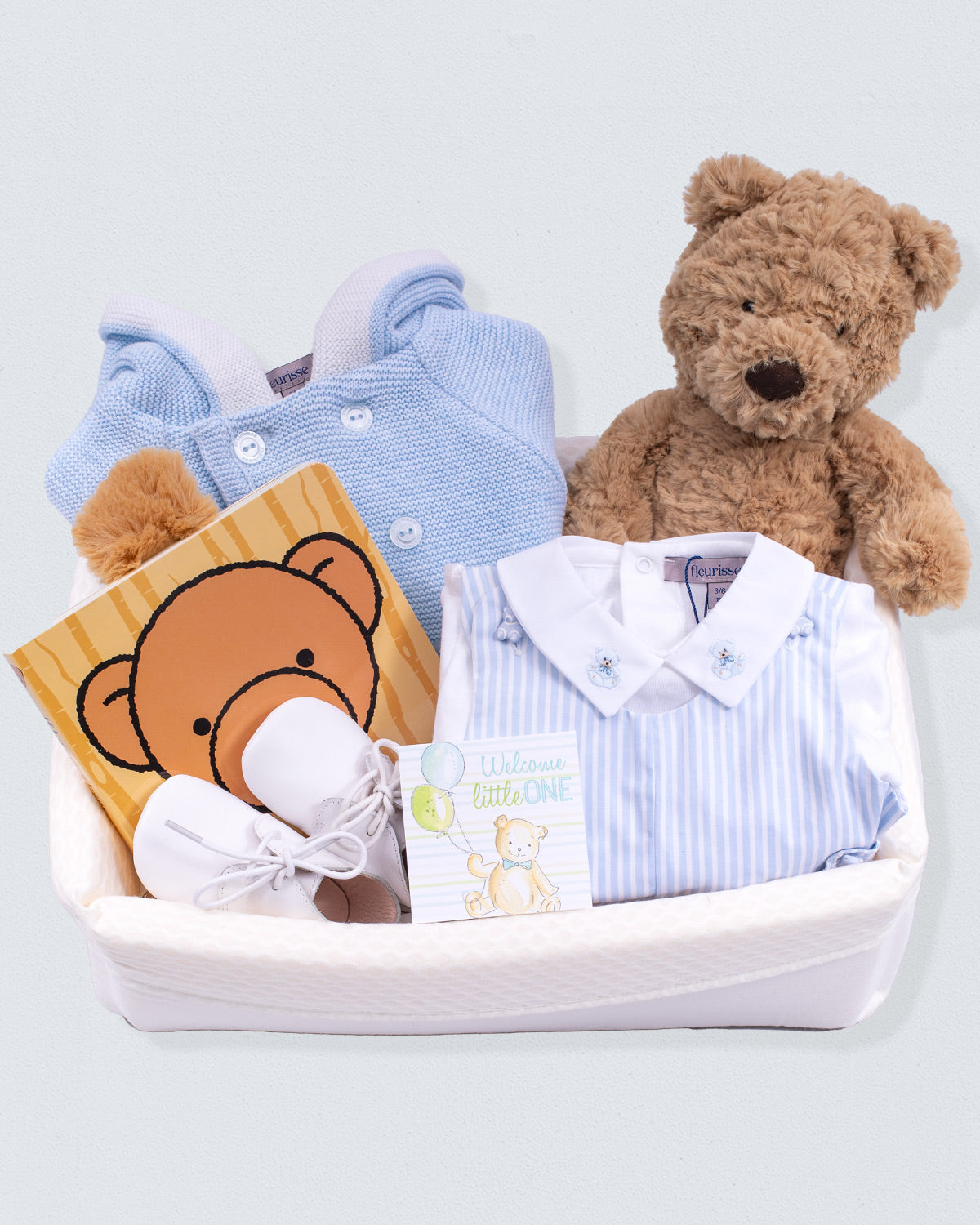 baby gift basket for boys featuring a greeting card, teddy baer and light blue sweater and romper.
