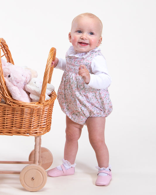 Baby girl wearing Kensington Lauren Pink Floral Romper pushing a carriage full of toy-showing the side of the romper