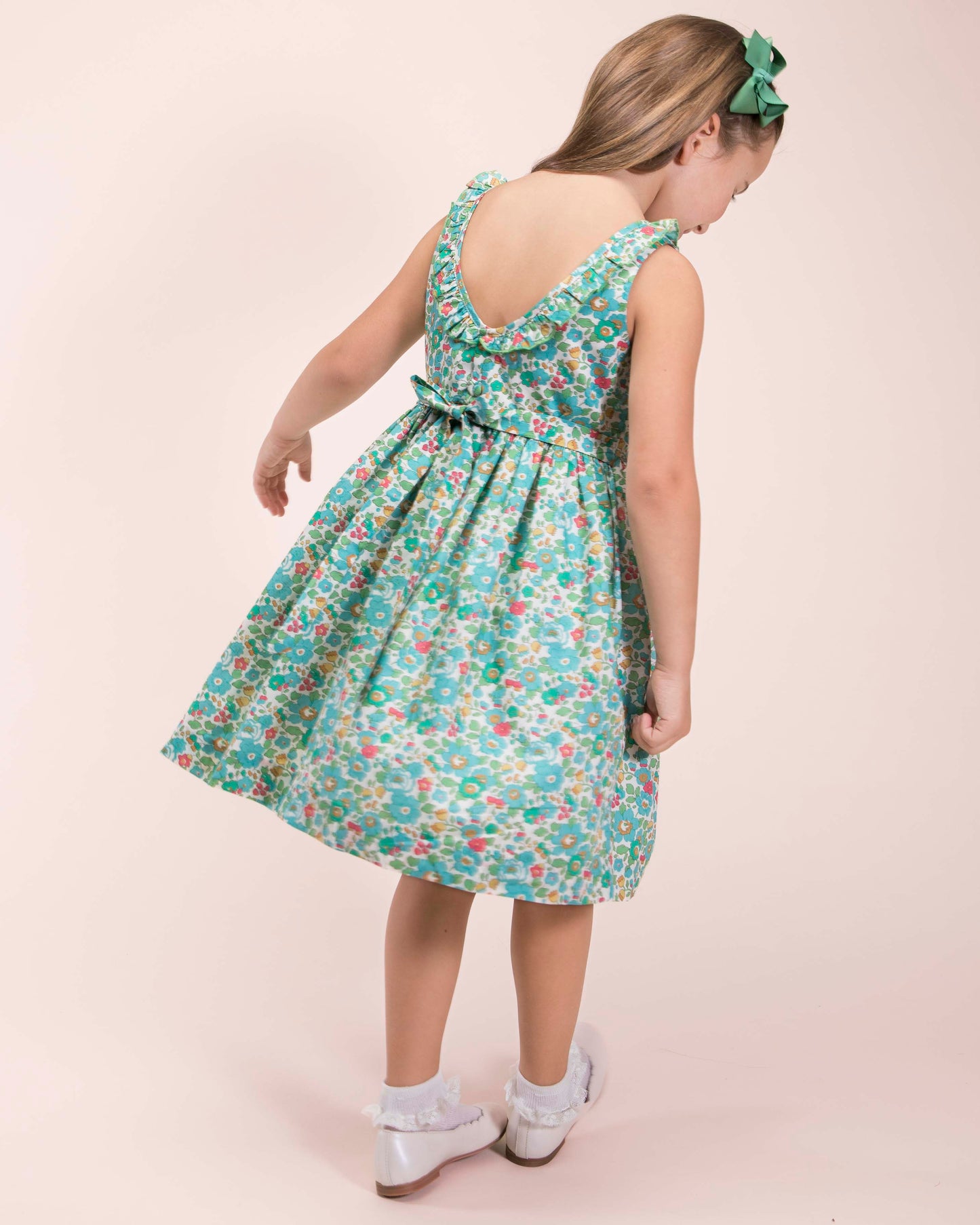 Girl looking down, twirling while wearing the Ella Liberty Betsy Mint Dress showing the back of the dress