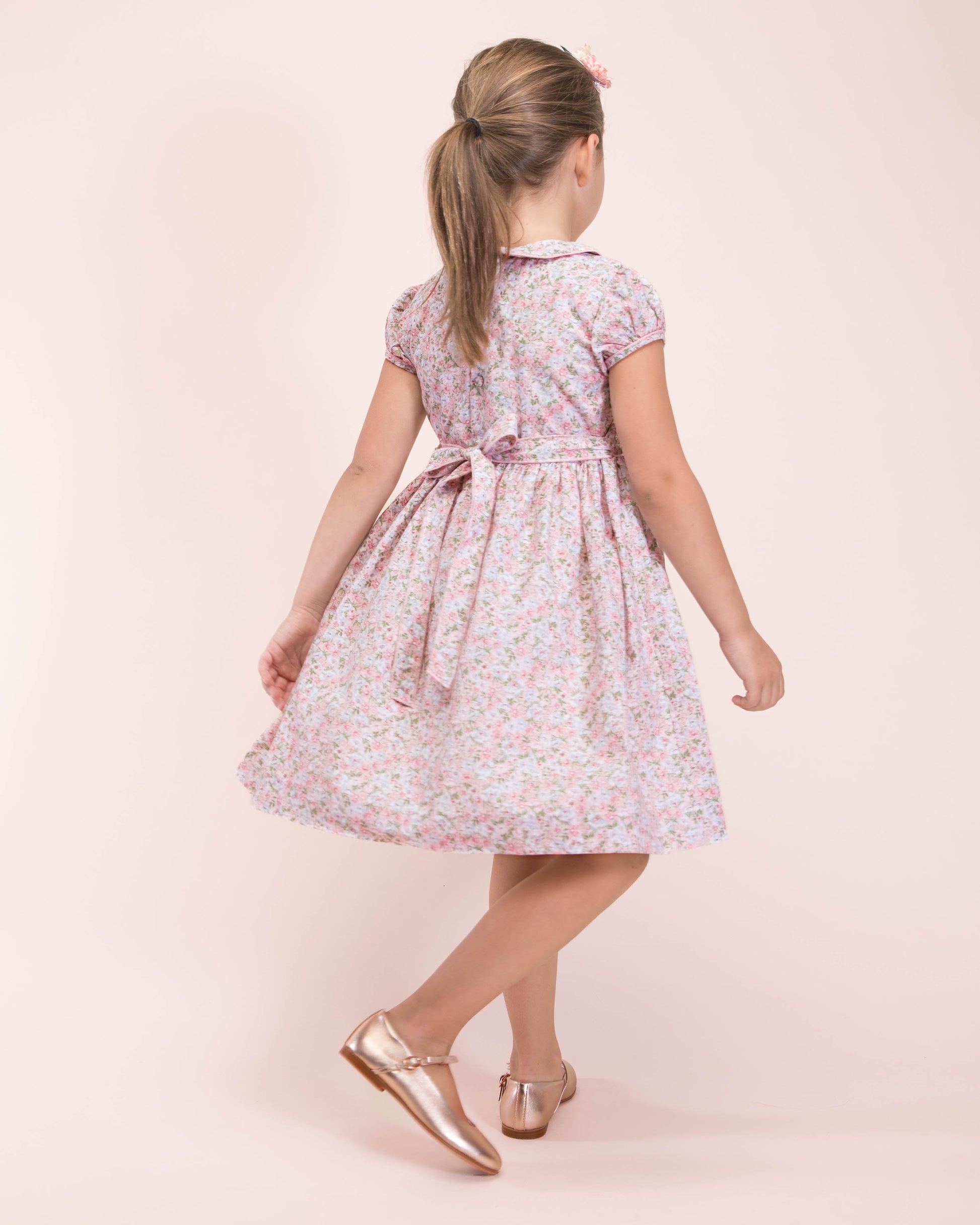 Back view of girl in pink floral smocked dress showing sash bow