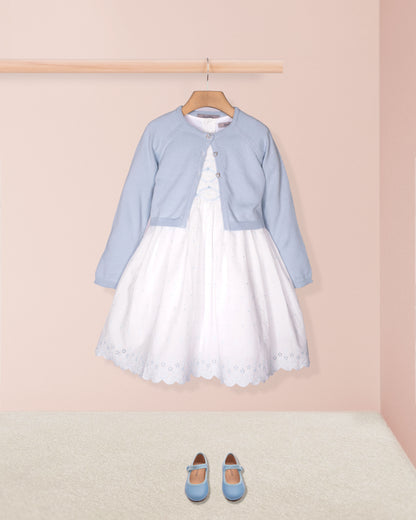 White dress with light blue cardigan and shoes on a pink background