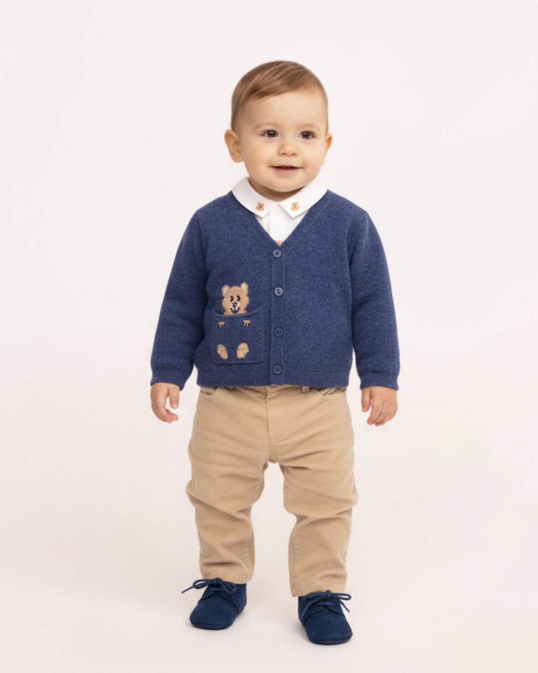 Child wearing a blue cardigan with a teddy bear design on a white background