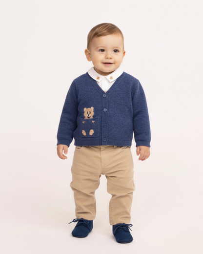 Child wearing a blue cardigan with a teddy bear design on a white background