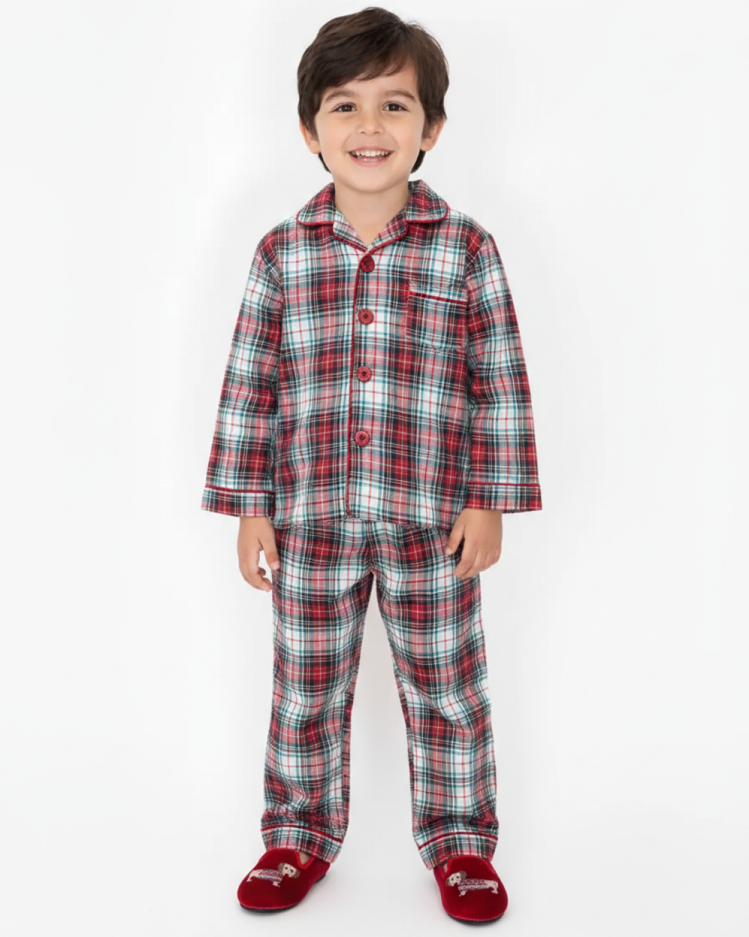 Child wearing a plaid longewear set with matching slippers on a white background