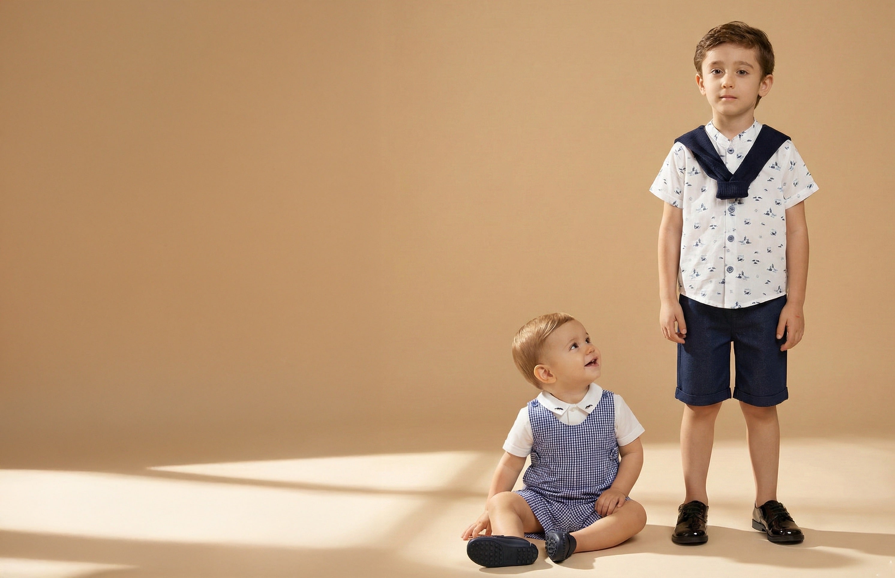 Two children in matching outfits on a beige background
