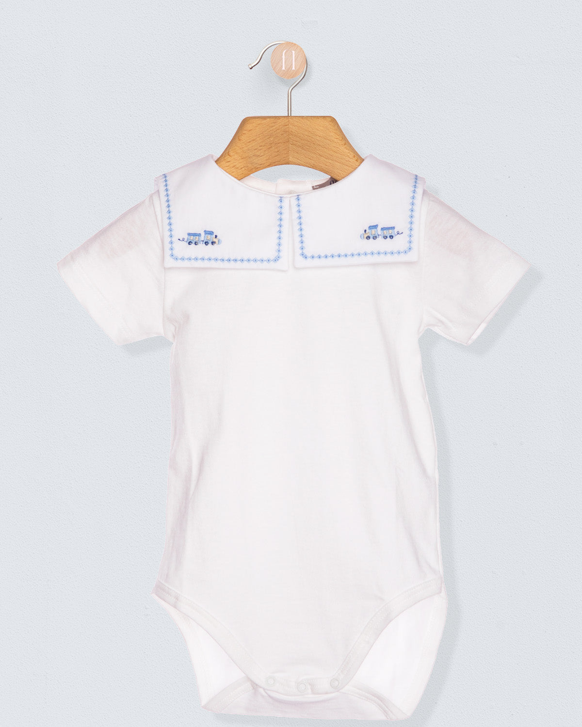 White baby bodysuit with blue trim on a wooden hanger against a light gray background