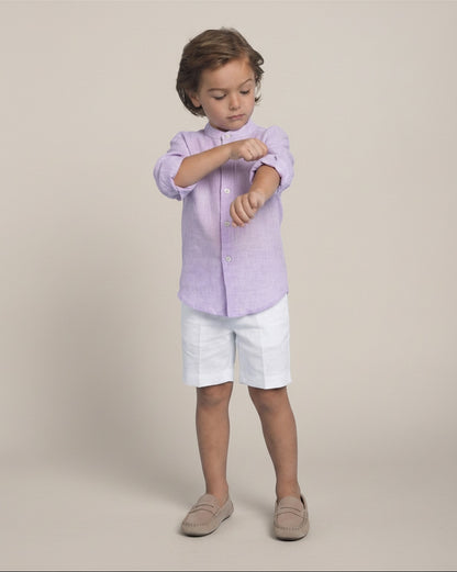 Child wearing a light purple shirt and white shorts on a beige background