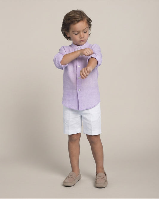 Child wearing a light purple shirt and white shorts on a beige background
