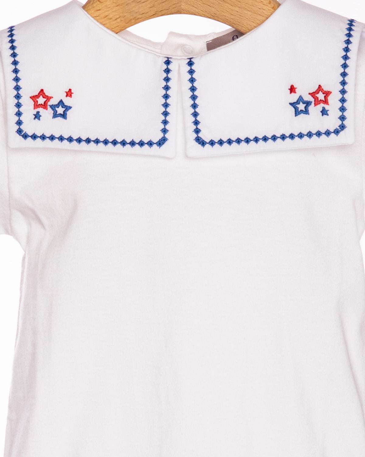 White top with red and blue star embroidery on a wooden hanger
