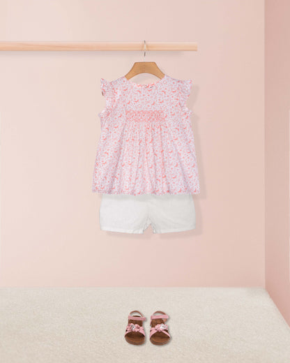 Children's outfit with floral top and white shorts on a pink background