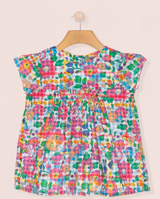 Colorful floral dress on a hanger against a beige background
