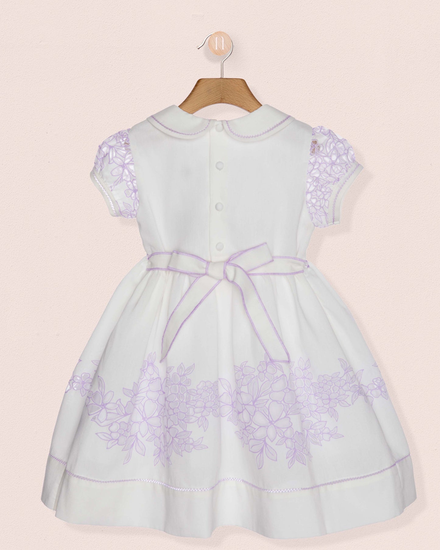 White dress with purple floral patterns on a beige background