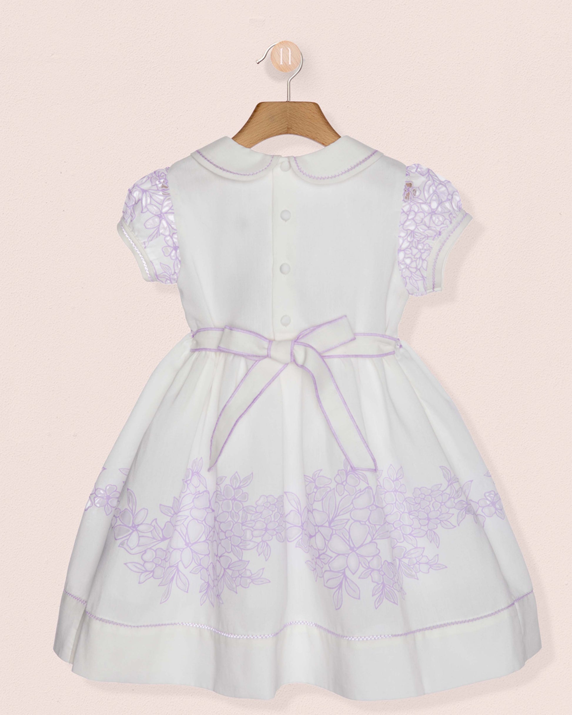 White dress with purple floral patterns on a beige background
