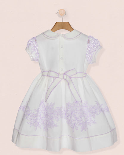 White dress with purple floral patterns on a beige background