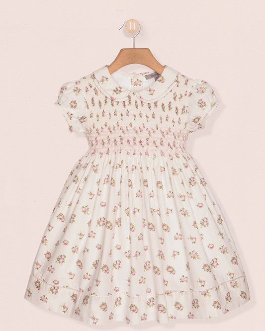Floral dress on a hanger against a light pink background
