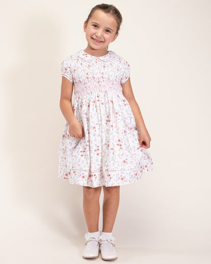 Girl turned to the front, wearing Emma Tuscany Pink Floral Smock Dress, showing the front of the dress