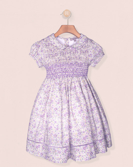 Lavender floral dress on a hanger against a beige background