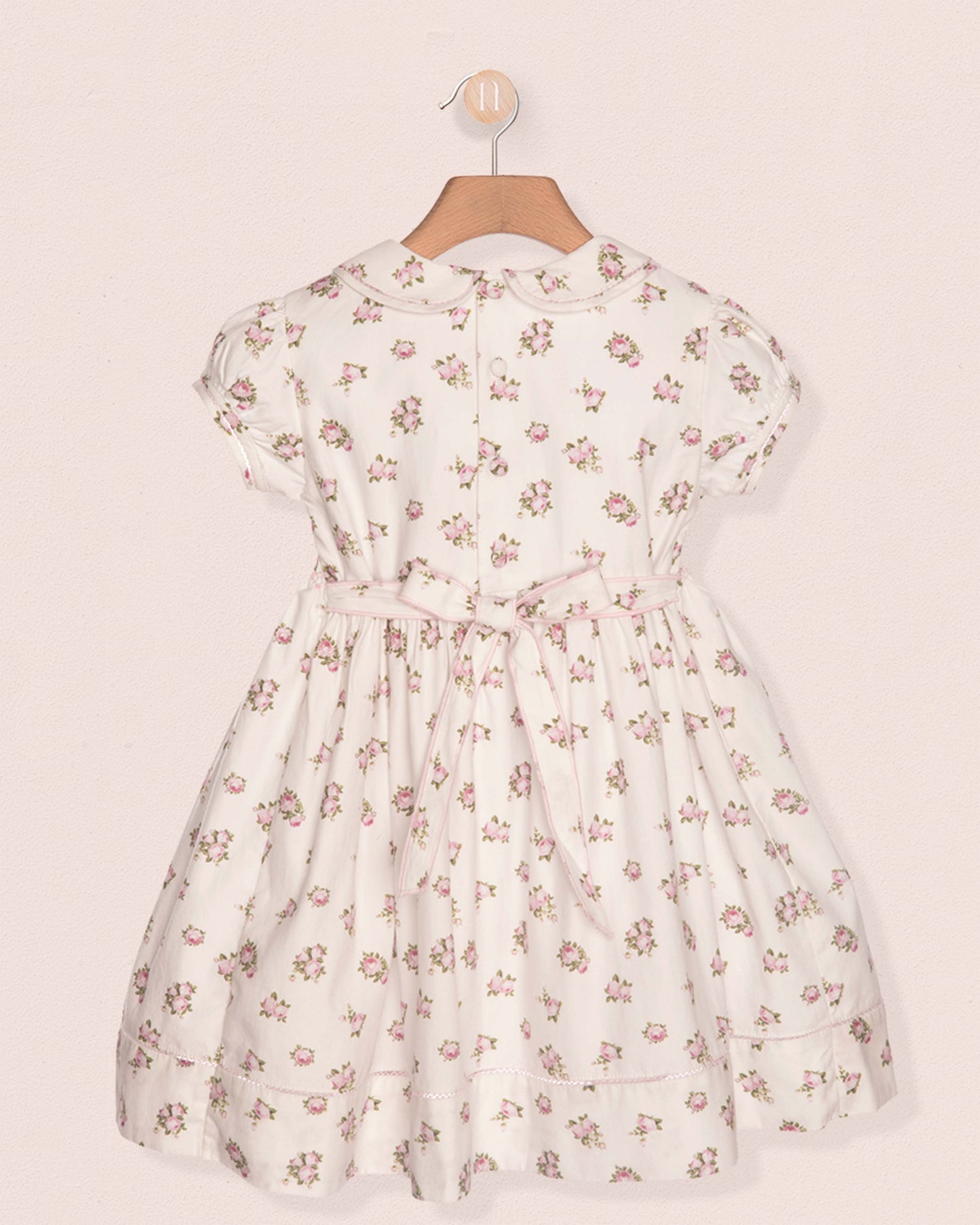 Floral dress on a hanger against a beige background