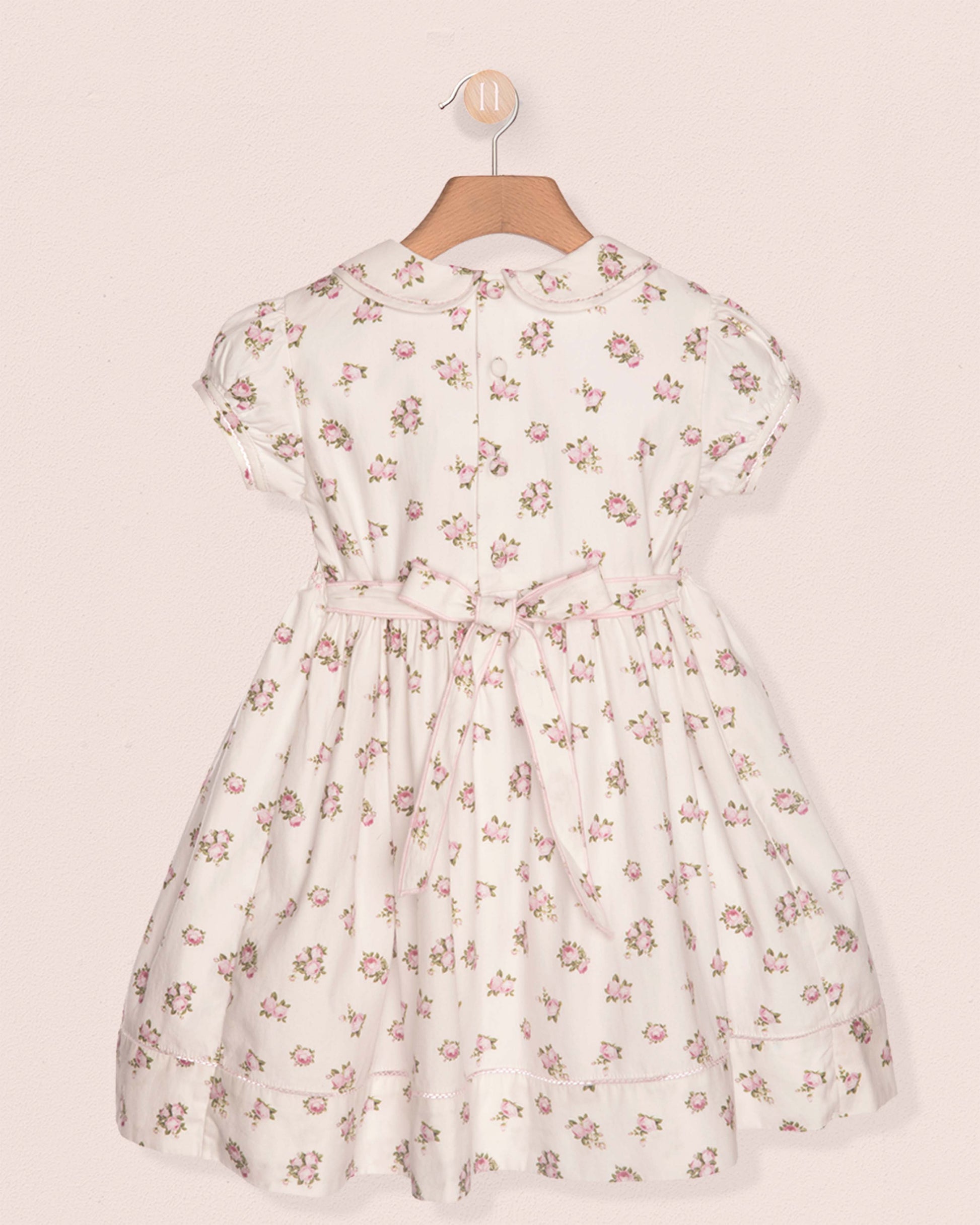 Floral dress on a hanger against a beige background