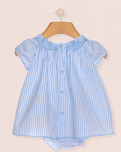 Blue and white striped blouse on a wooden hanger against a beige background