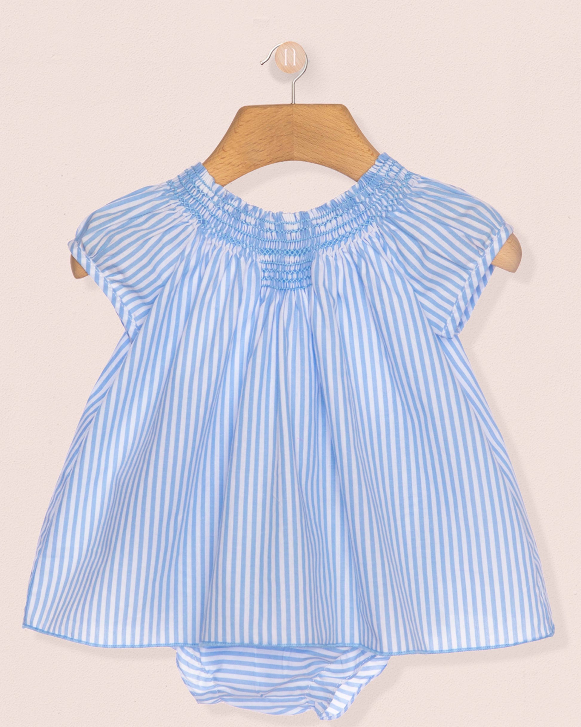 Blue and white striped baby dress on a hanger against a beige background