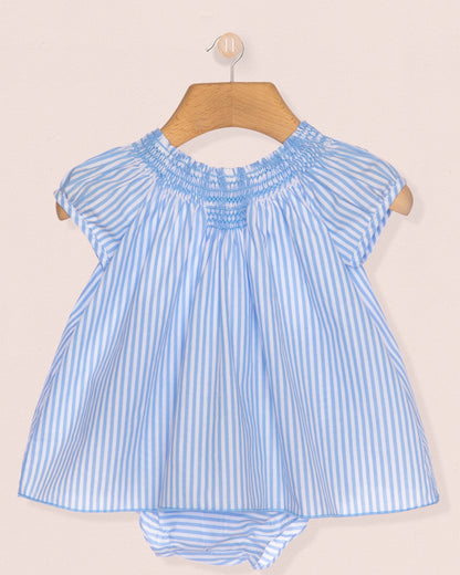 Blue and white striped baby dress on a hanger against a beige background