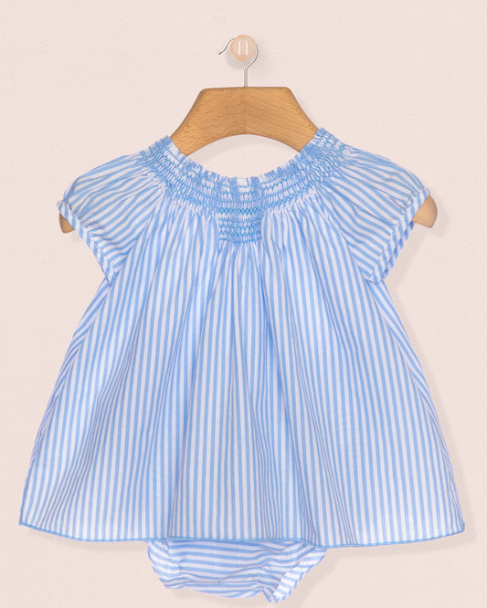 Blue and white striped baby dress on a hanger against a beige background