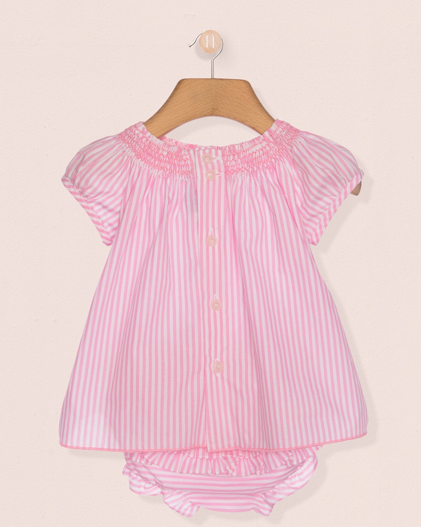 Pink and white striped baby outfit on a hanger against a beige background