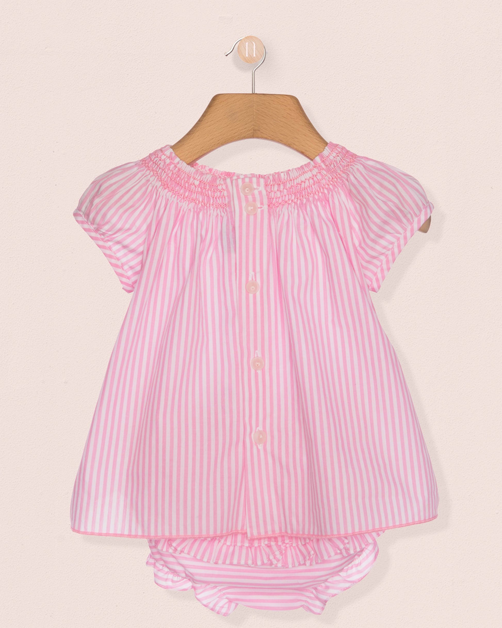 Pink and white striped baby outfit on a hanger against a beige background